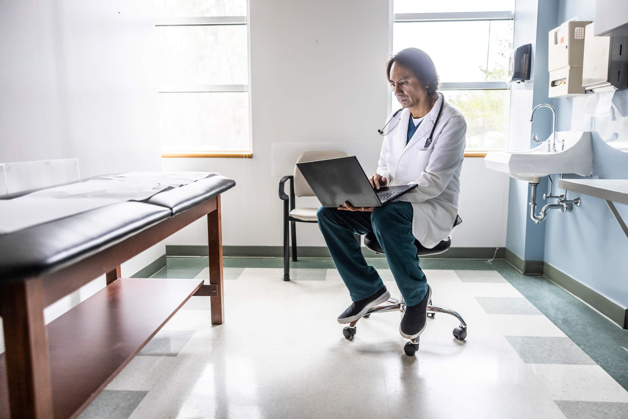 Doctor using laptop in exam room